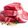 Raw beef steaks stacked with garlic, herbs and pepper on white background, fresh meat for cooking and barbecue